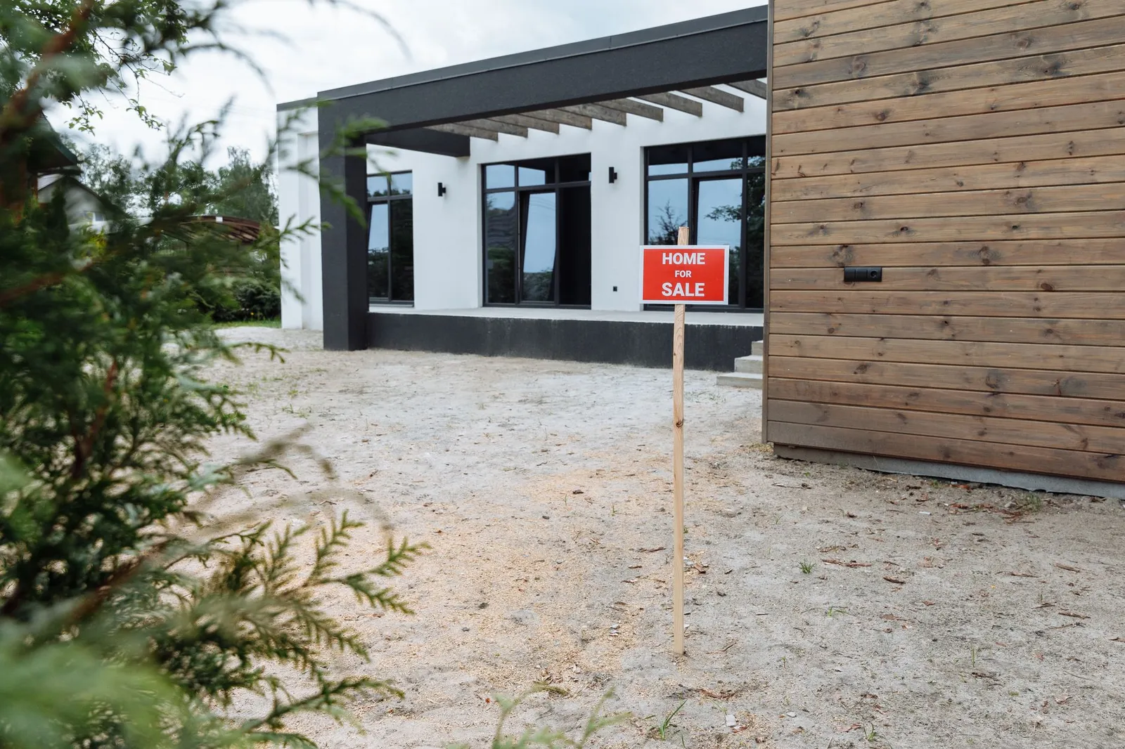 A house with a red home for sale sign staked in the front yard