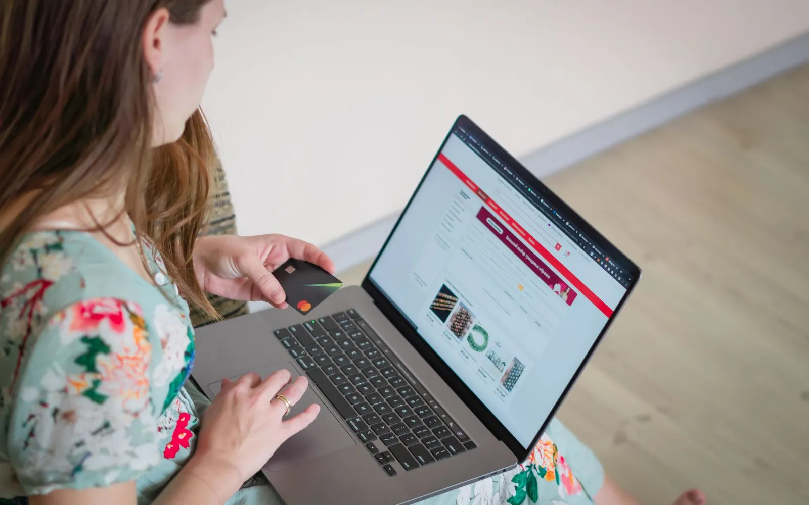A person at a table using a laptop while holding a payment card