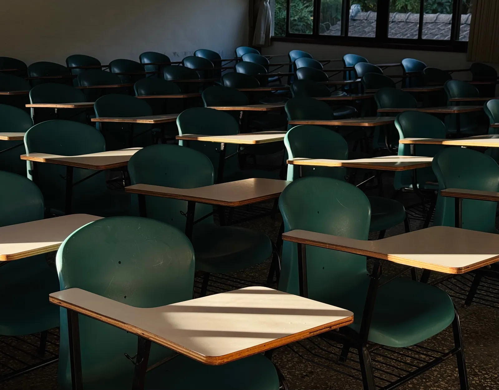 Rows of empty classroom desks catching late afternoon sunlight