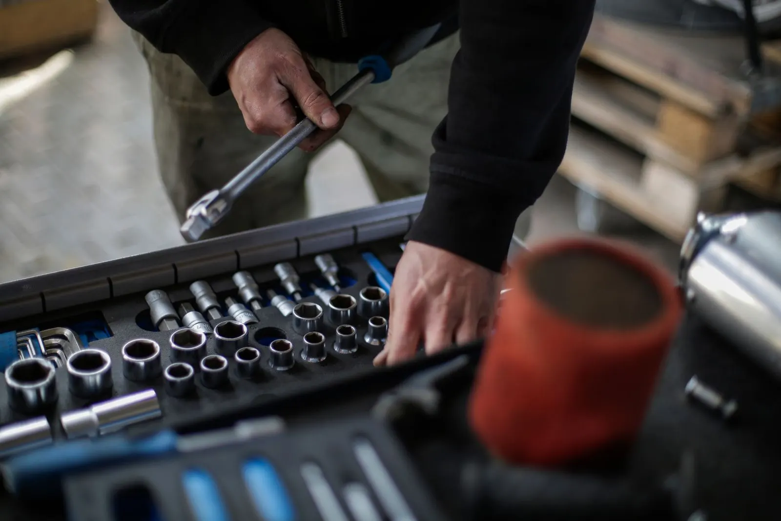 Mechanic with a ratchet reaching into a tray of sockets in a repair shop