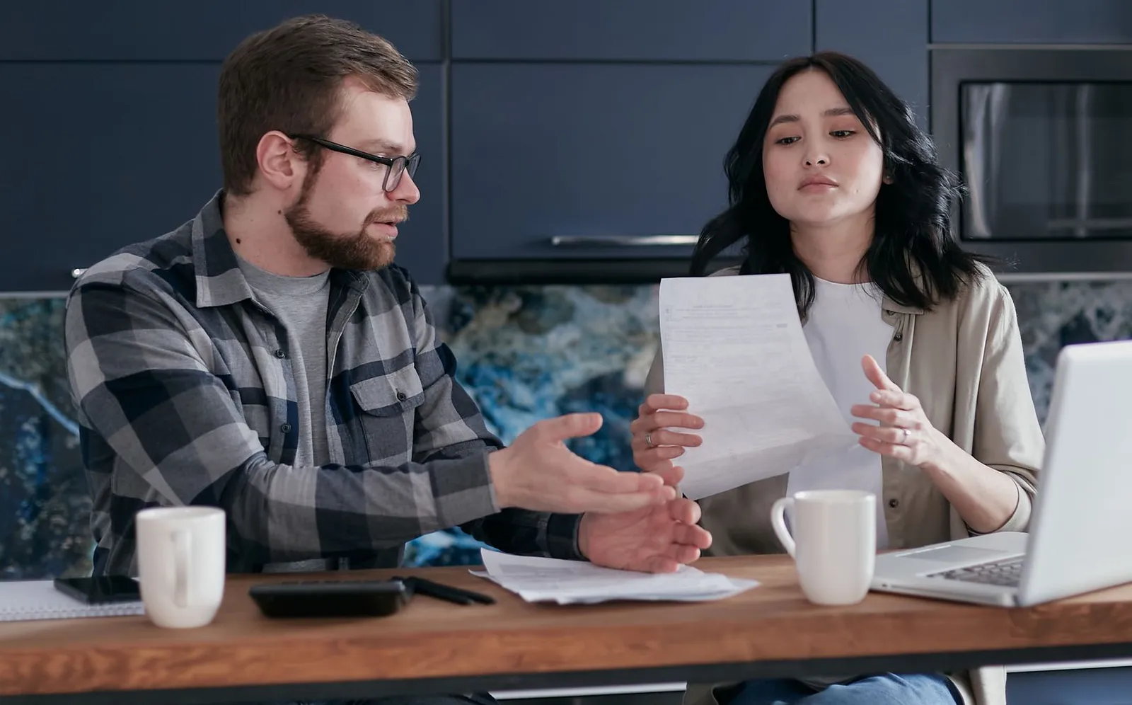 Couple going over paperwork and a laptop at a kitchen table