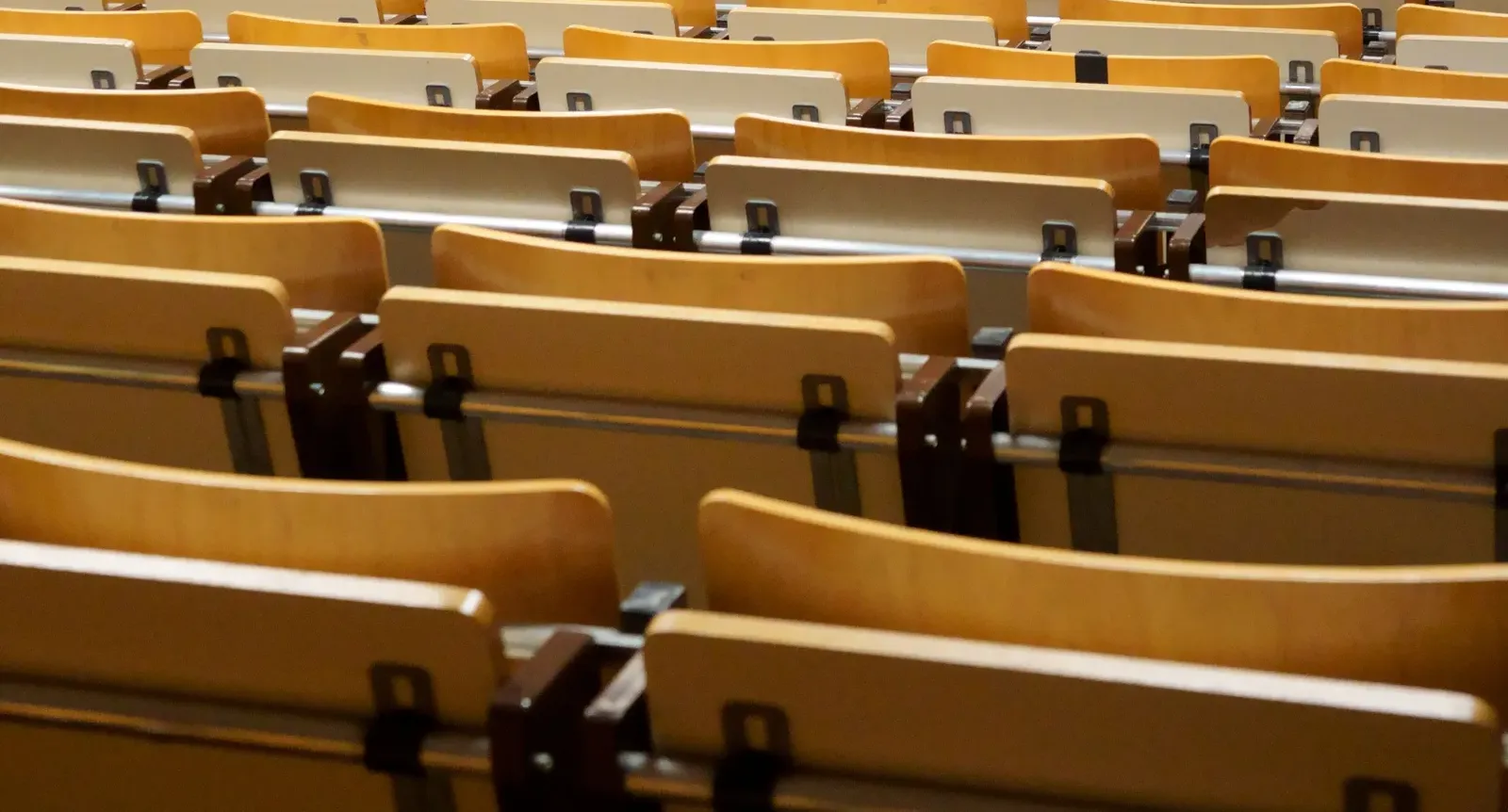 Rows of empty wooden seats in a university lecture hall
