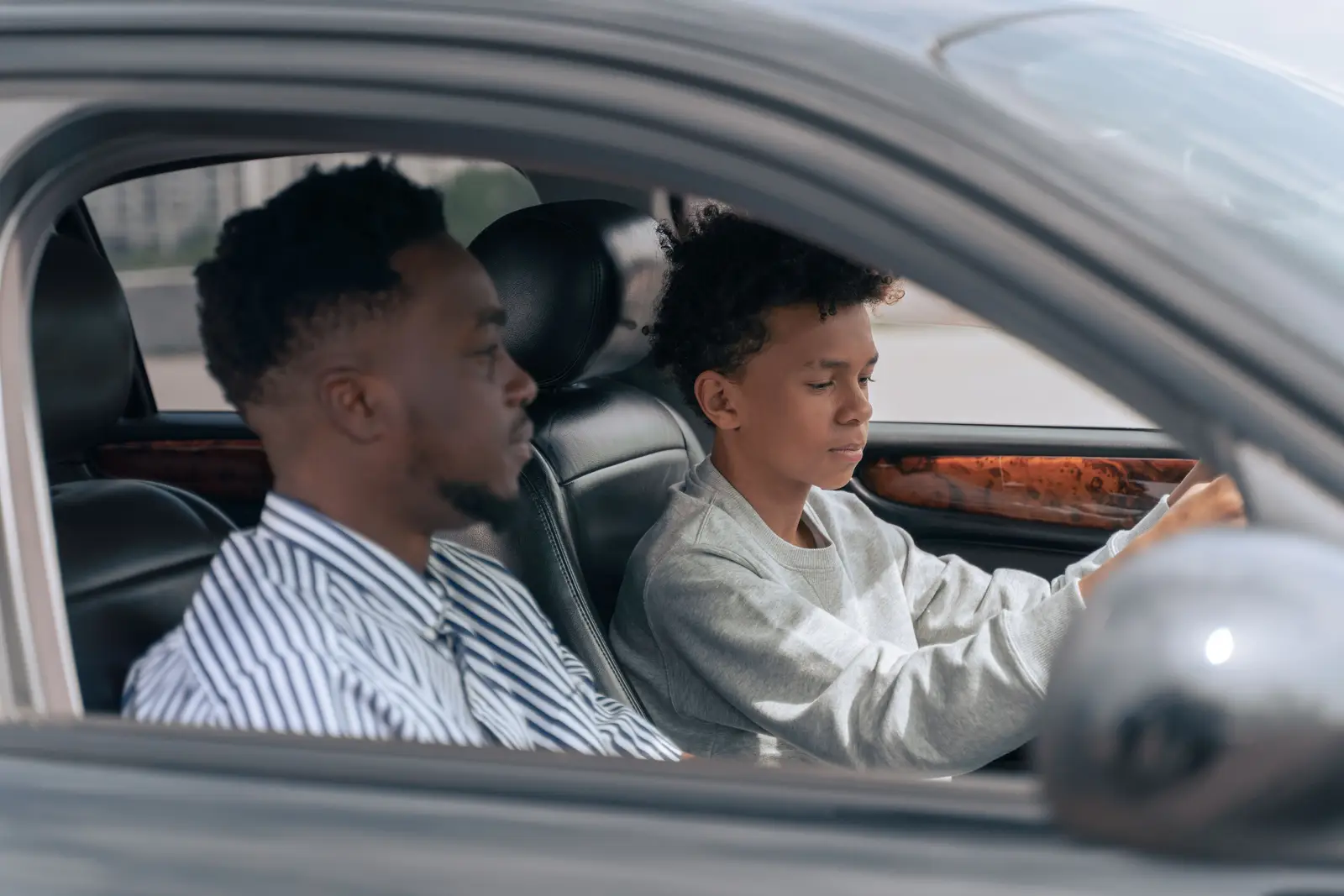 A father sits in the passenger seat while his teenage son drives