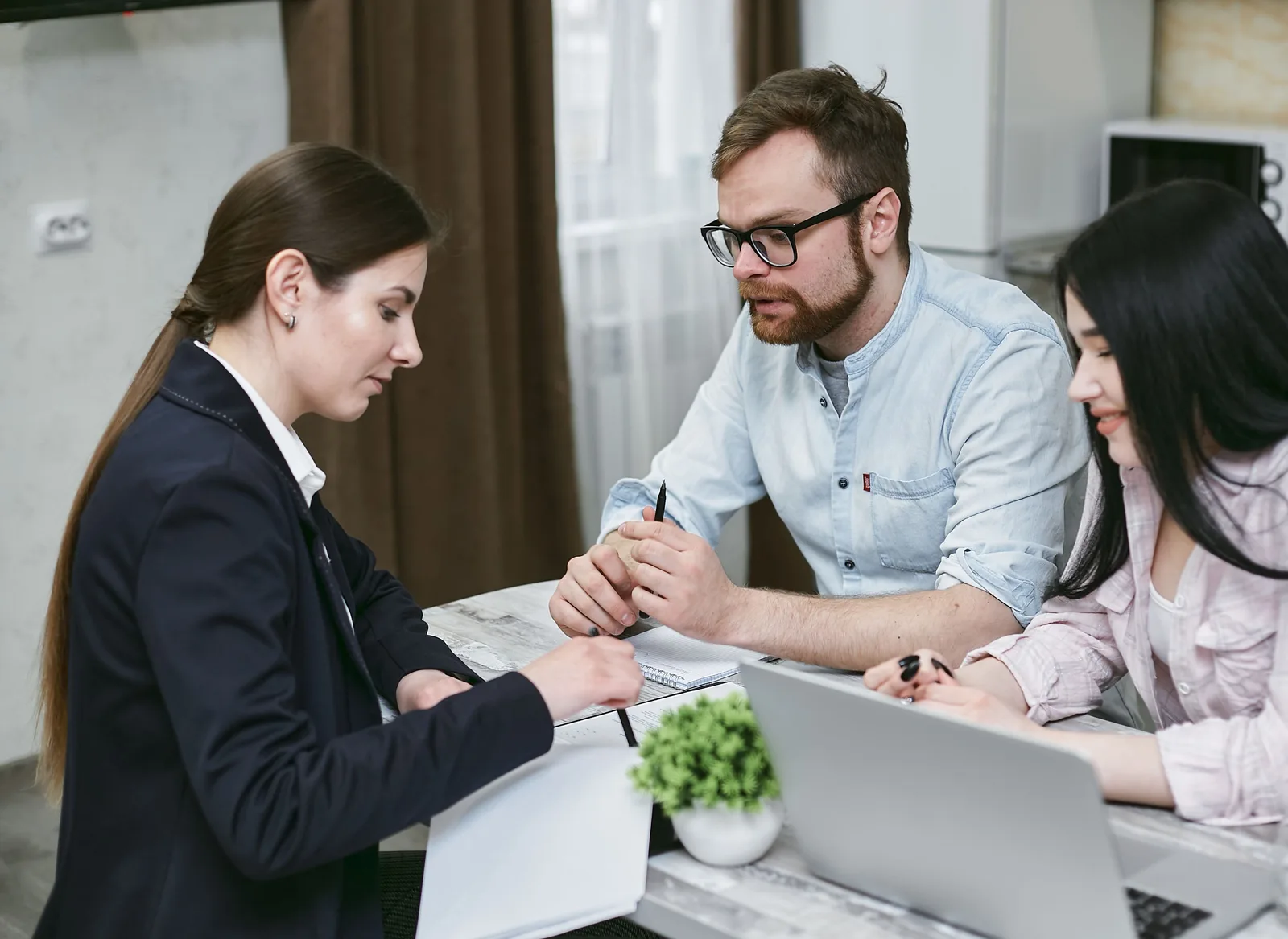 A couple reviewing financial documents with an advisor at a table