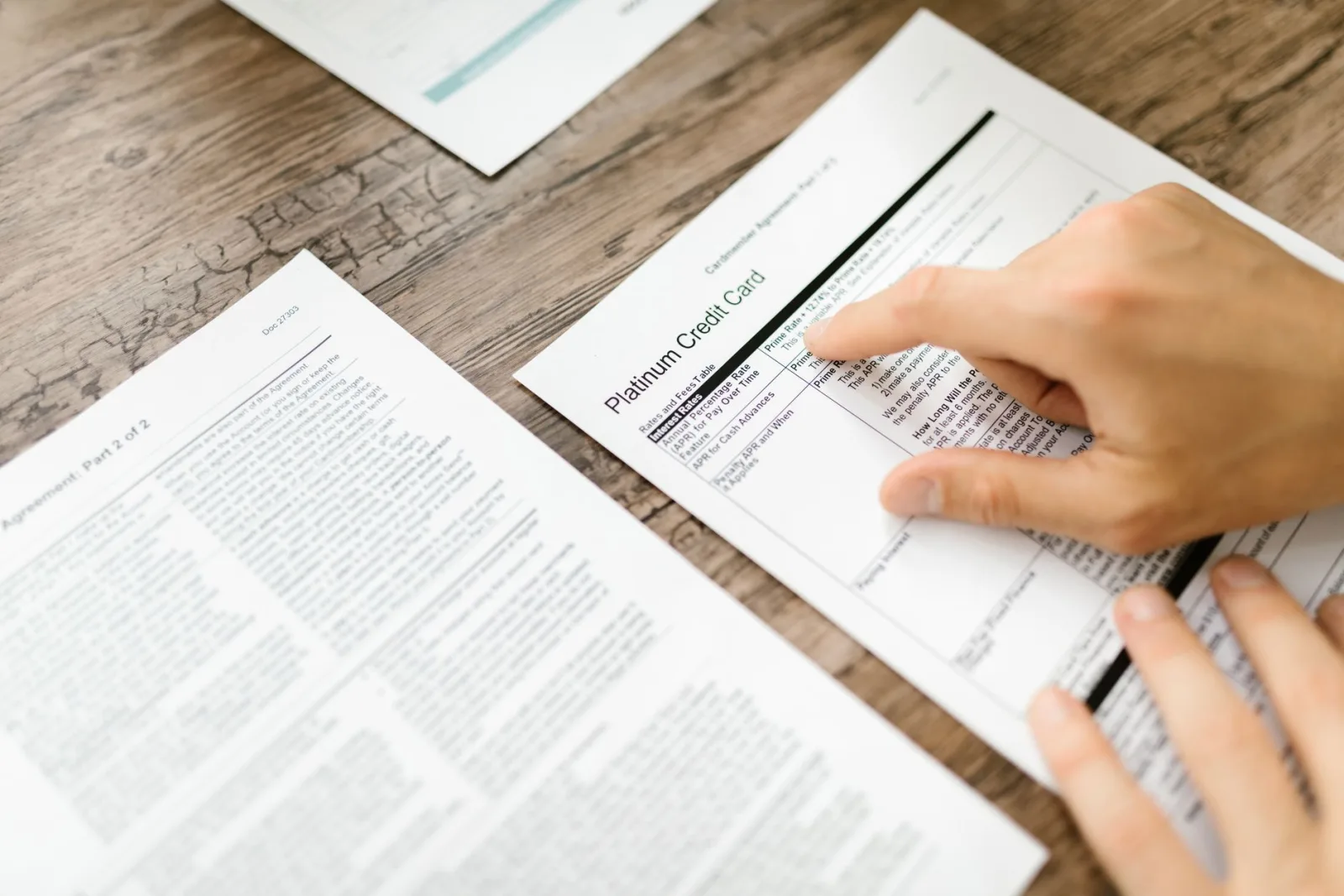 A hand reading the rates and fees table on a printed credit card agreement