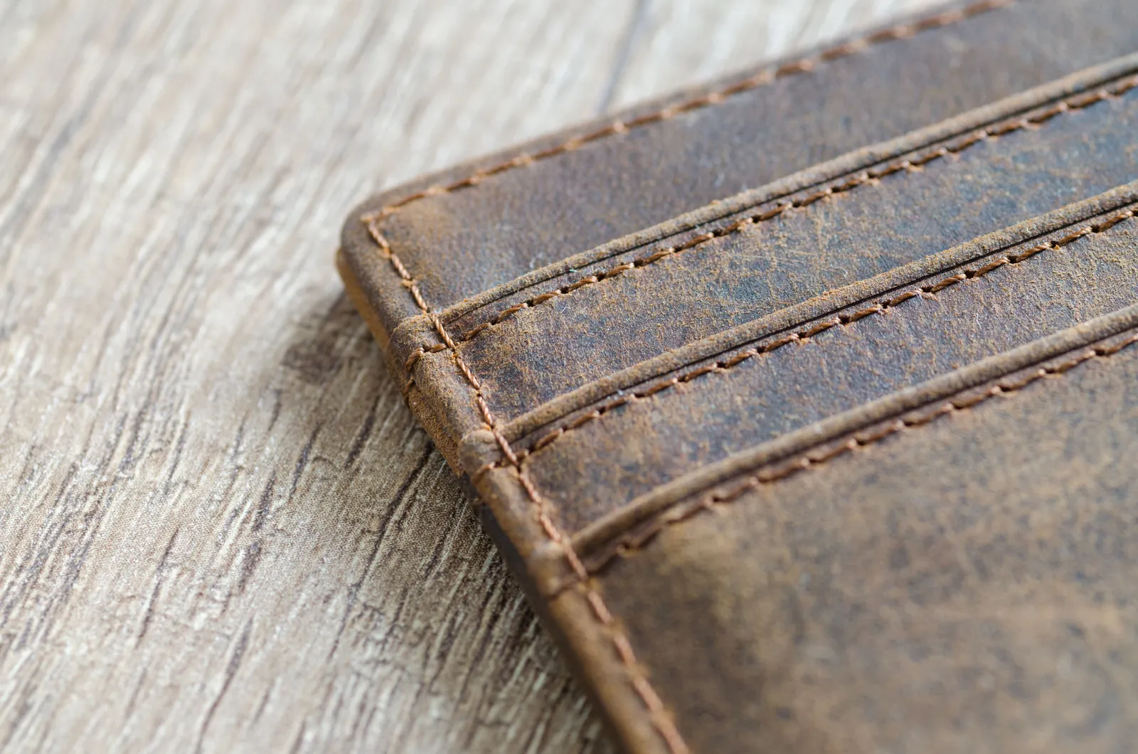 Worn brown leather wallet lying on a wooden table