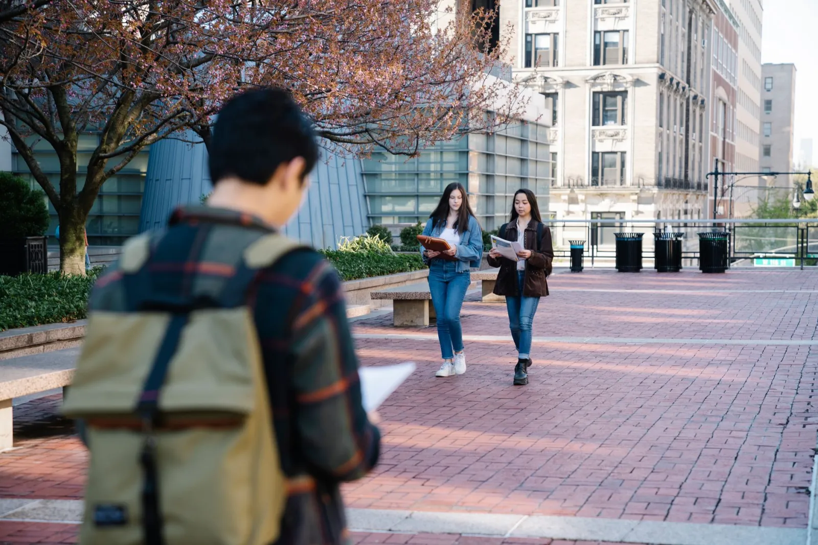 Students carrying books and backpacks walking along a campus street
