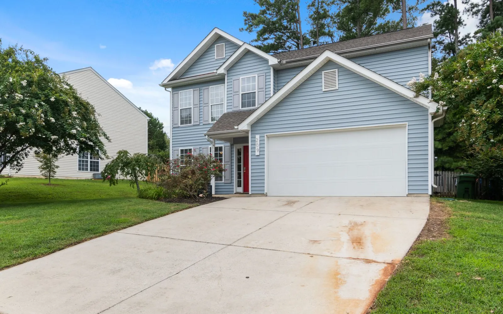 A two-story suburban house with a driveway and front lawn
