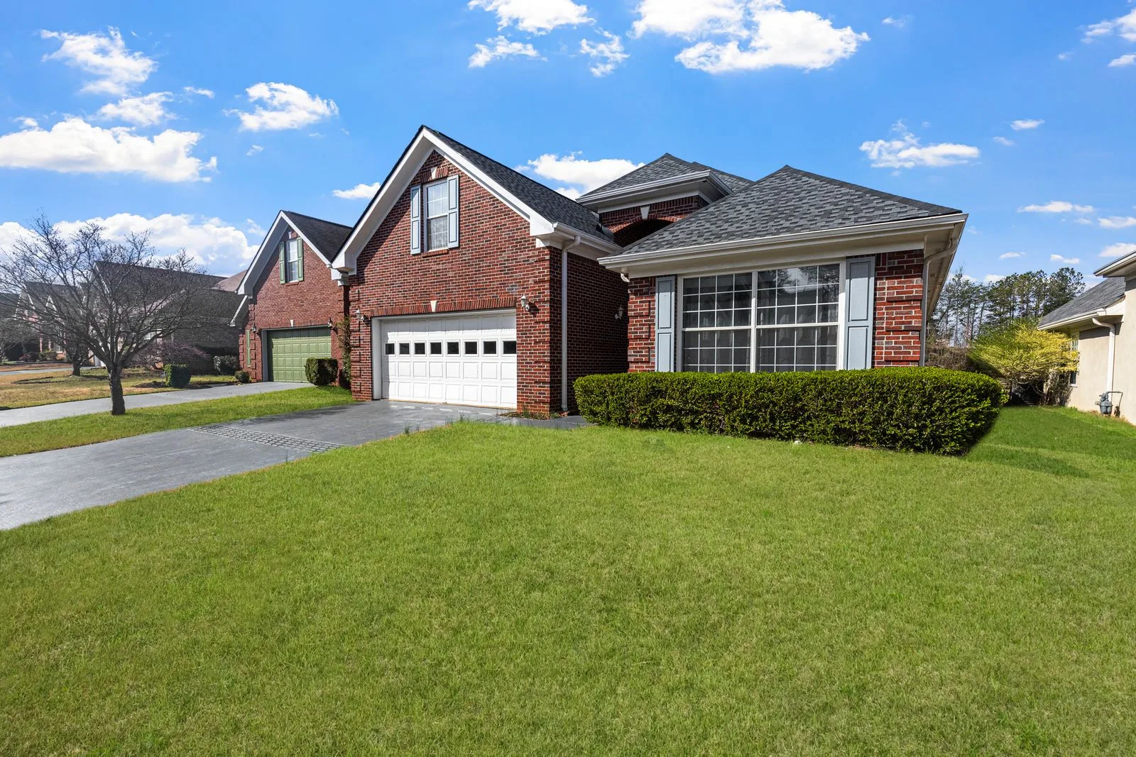 A red brick suburban house with a shingled roof and a front lawn